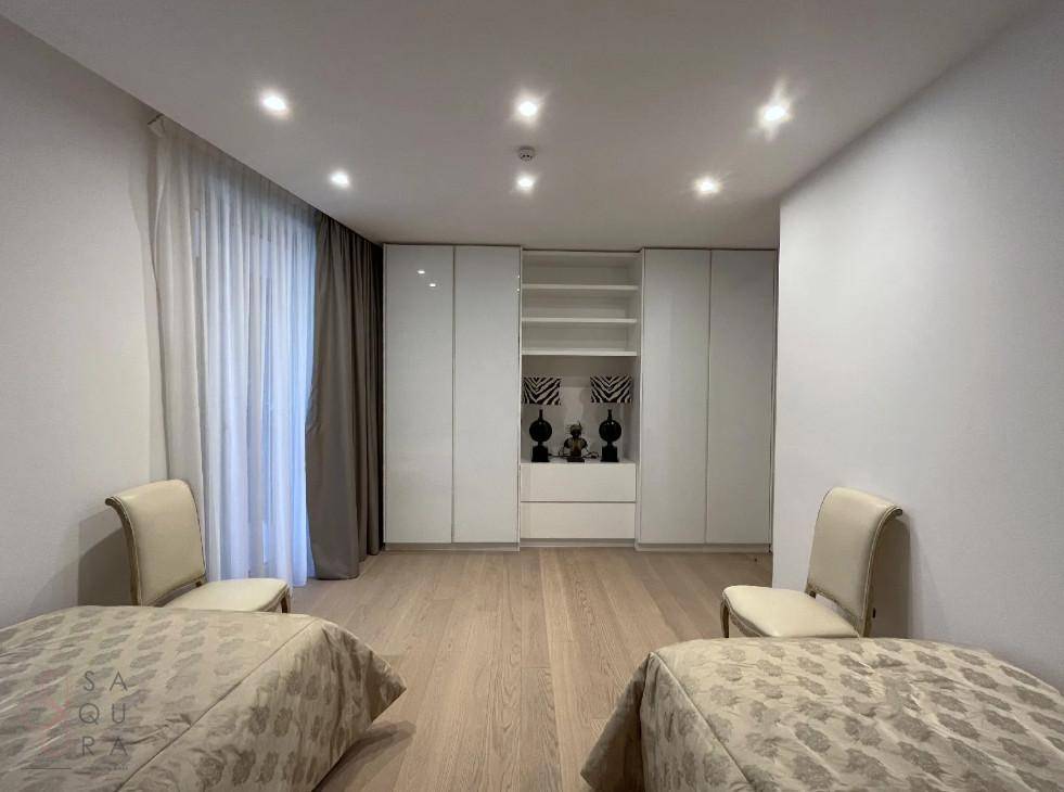 Helles Schlafzimmer mit Holzboden und eleganten weißen Einbauschränken.