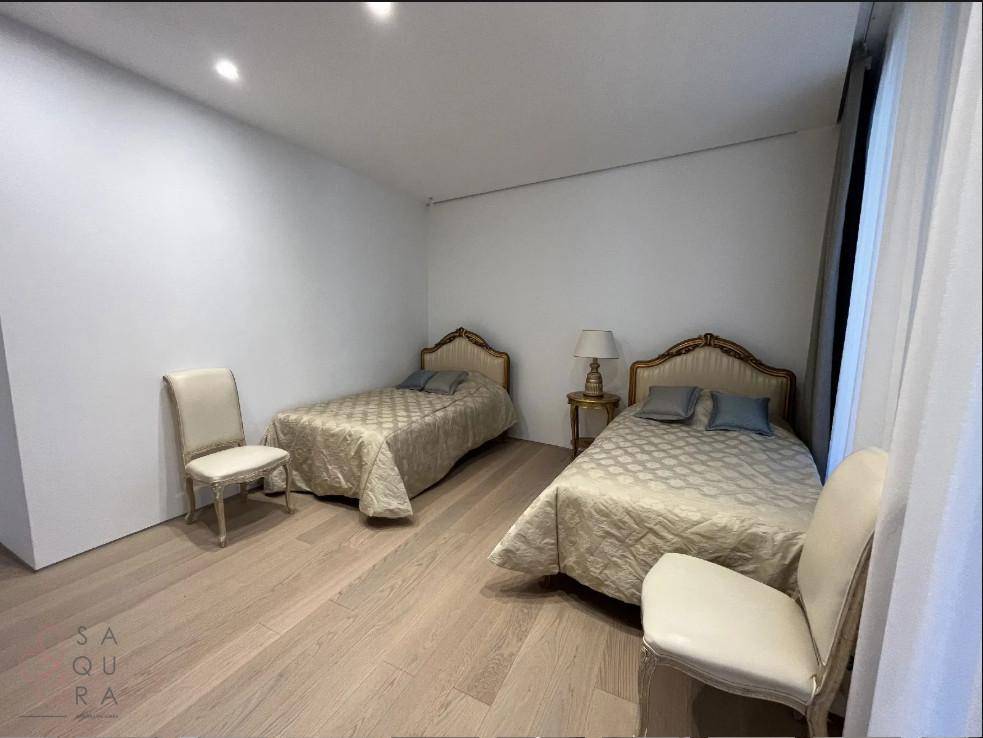 Gemütliches Schlafzimmer mit zwei Einzelbetten, Holzboden und schlichten weißen Wänden.