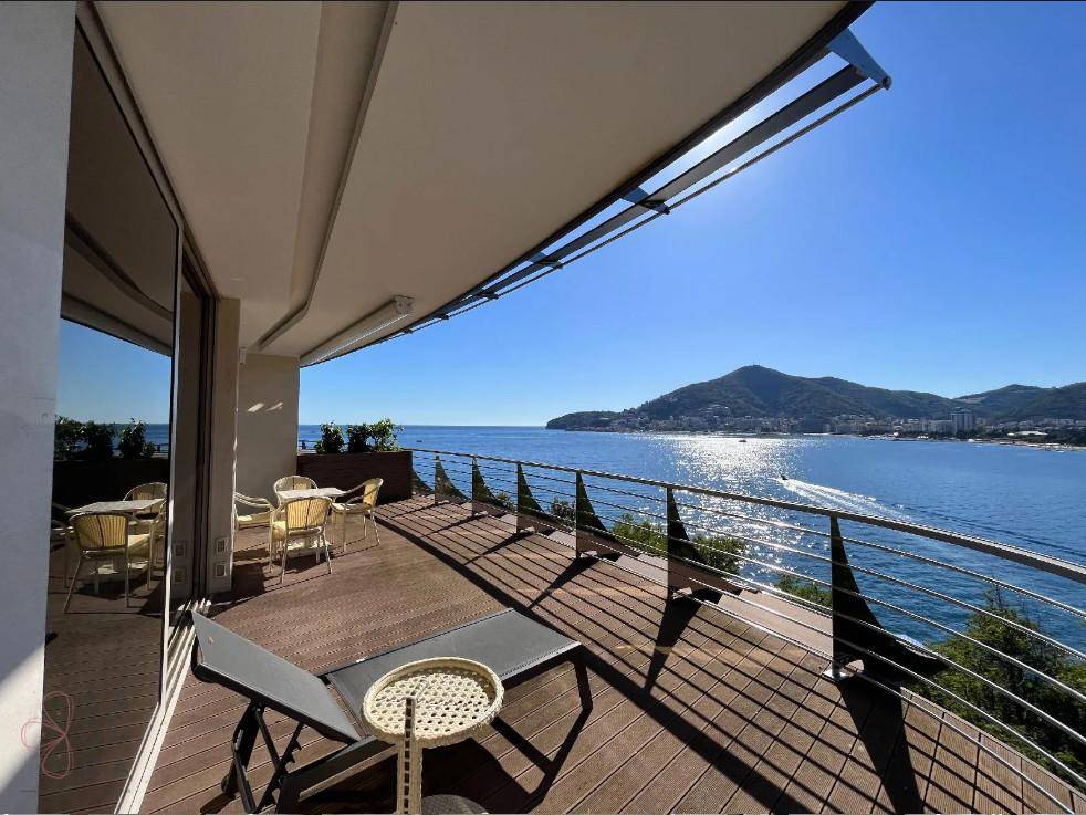 Weitläufige Terrasse mit Liegestuhl, Holzboden und Panoramablick auf das Meer.