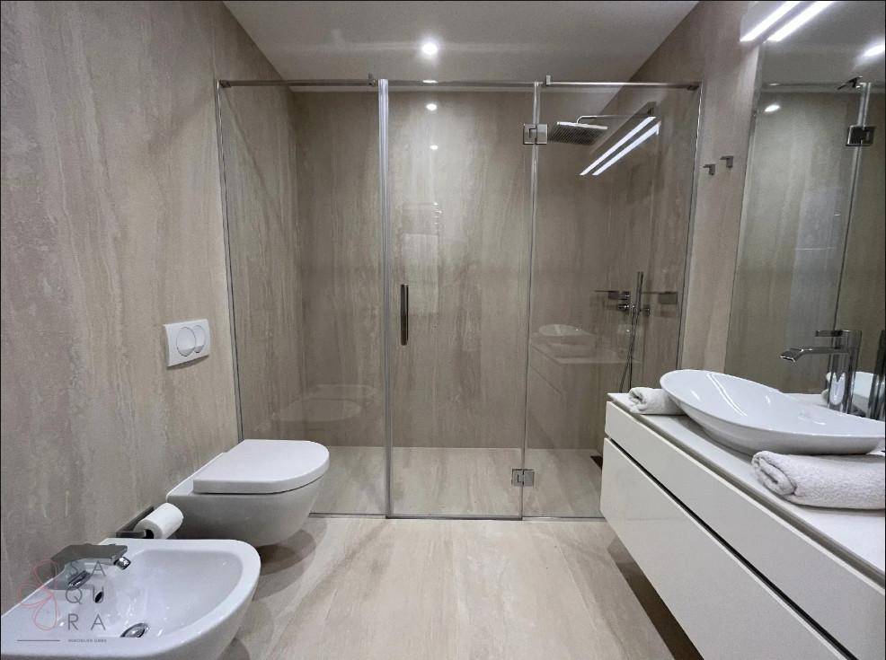 Elegantes Badezimmer mit begehbarer Dusche, Bidet und modernem Doppelwaschbecken.