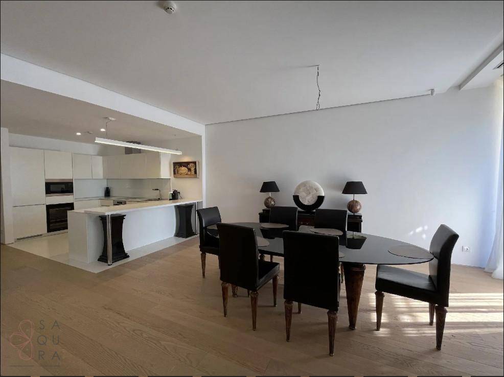 Eleganter Essbereich mit dunklem Tisch und Stühlen, angrenzend an eine moderne weiße Küche.