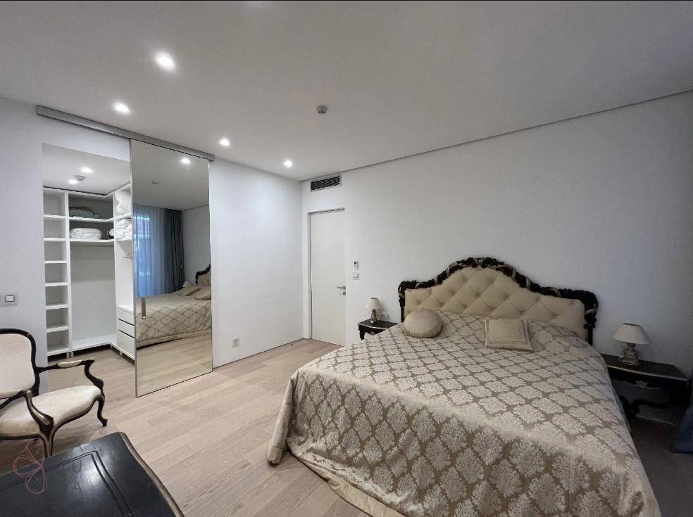 Geräumiges Schlafzimmer mit großem Bett, Spiegelschiebetüren und hellem Holzfußboden.