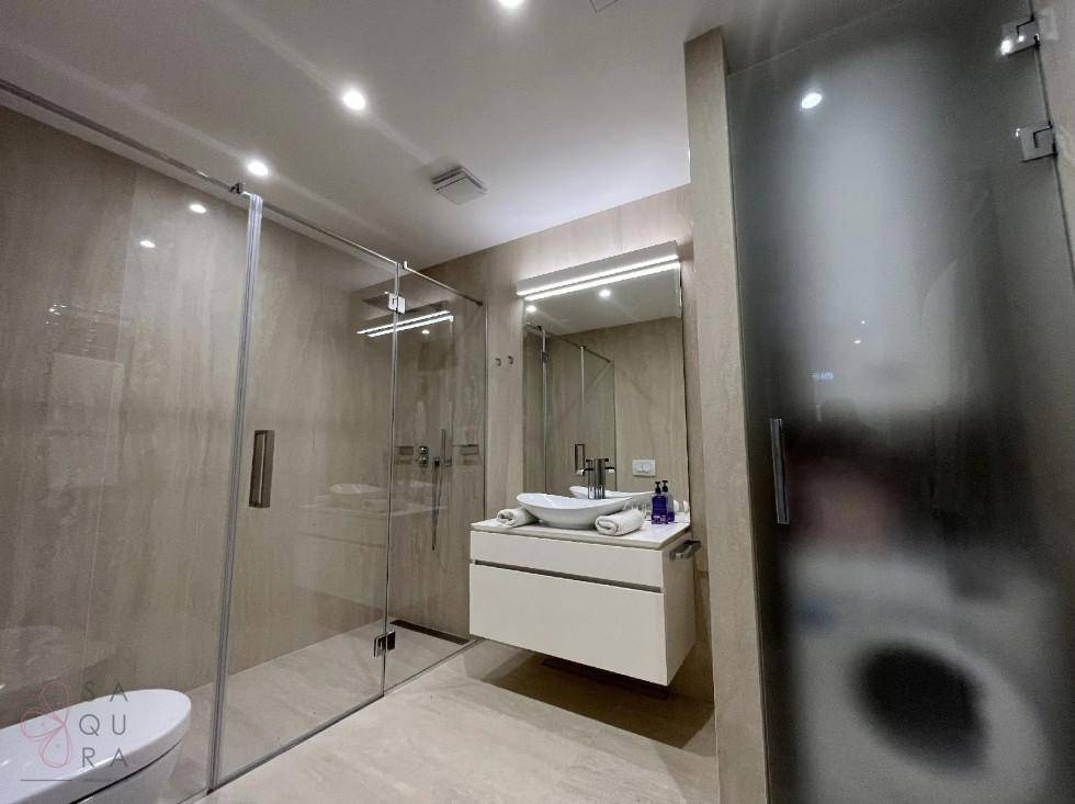 Modernes Badezimmer mit begehbarer Dusche, schwebendem Waschtisch und großem Spiegel.