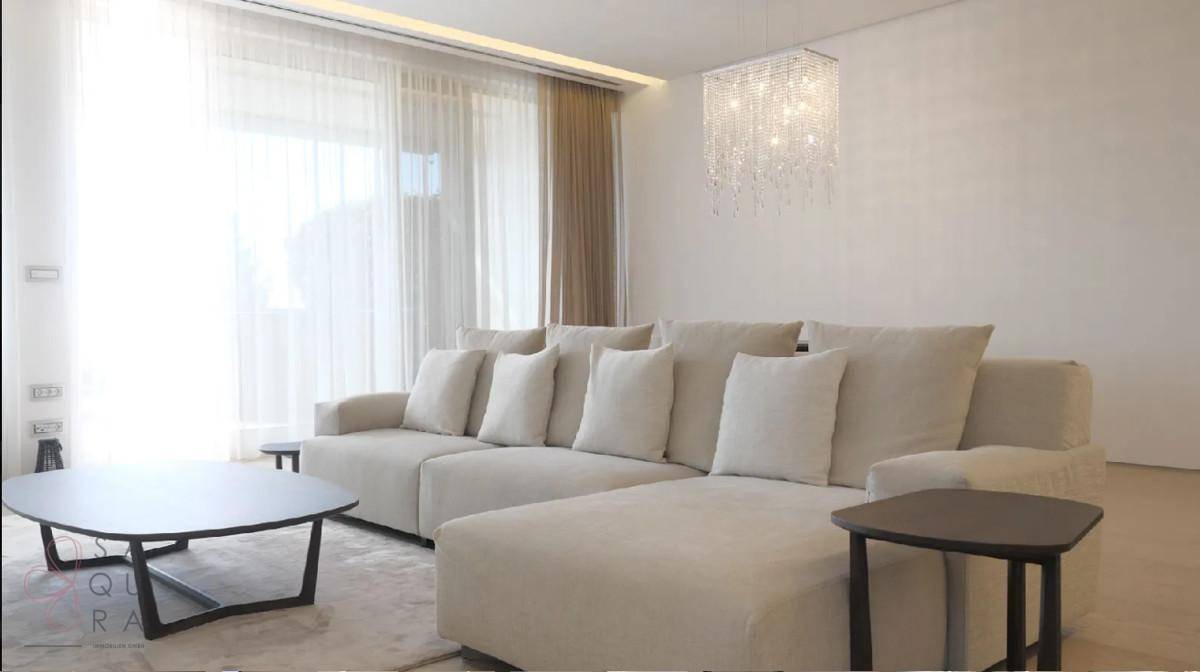 Gemütliches Wohnzimmer mit großem Ecksofa, elegantem Kronleuchter und viel Tageslicht.