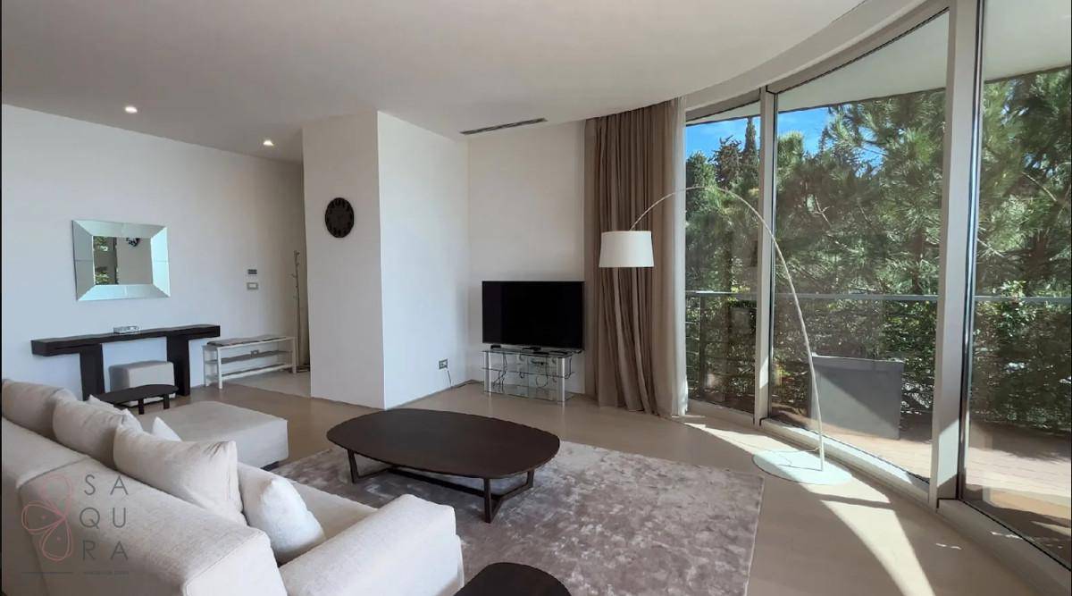 Modernes Wohnzimmer mit geschwungenen Panoramafenstern und Blick ins Grüne.