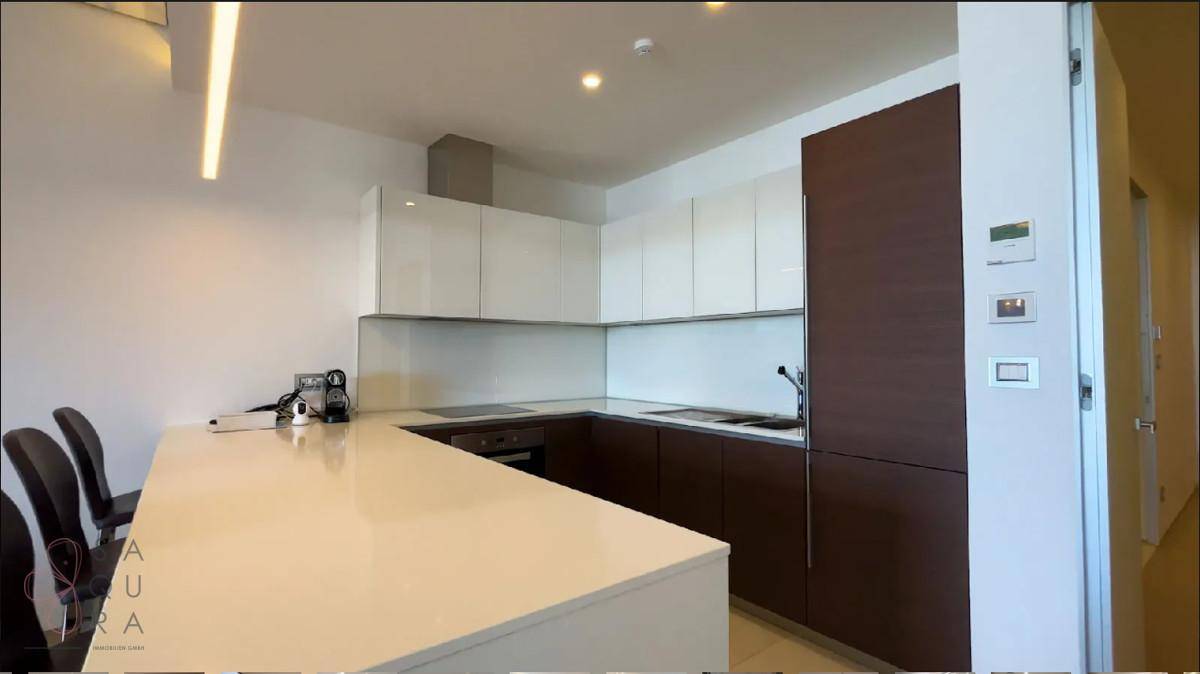 Moderne Küche mit weißer Arbeitsplatte, glänzenden Oberschränken und dunklen Unterschränken.