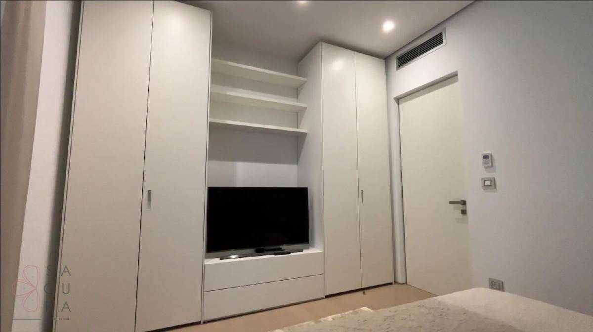 Schlafzimmer mit integrierten weißen Kleiderschränken, Regalen und einem Fernseher.