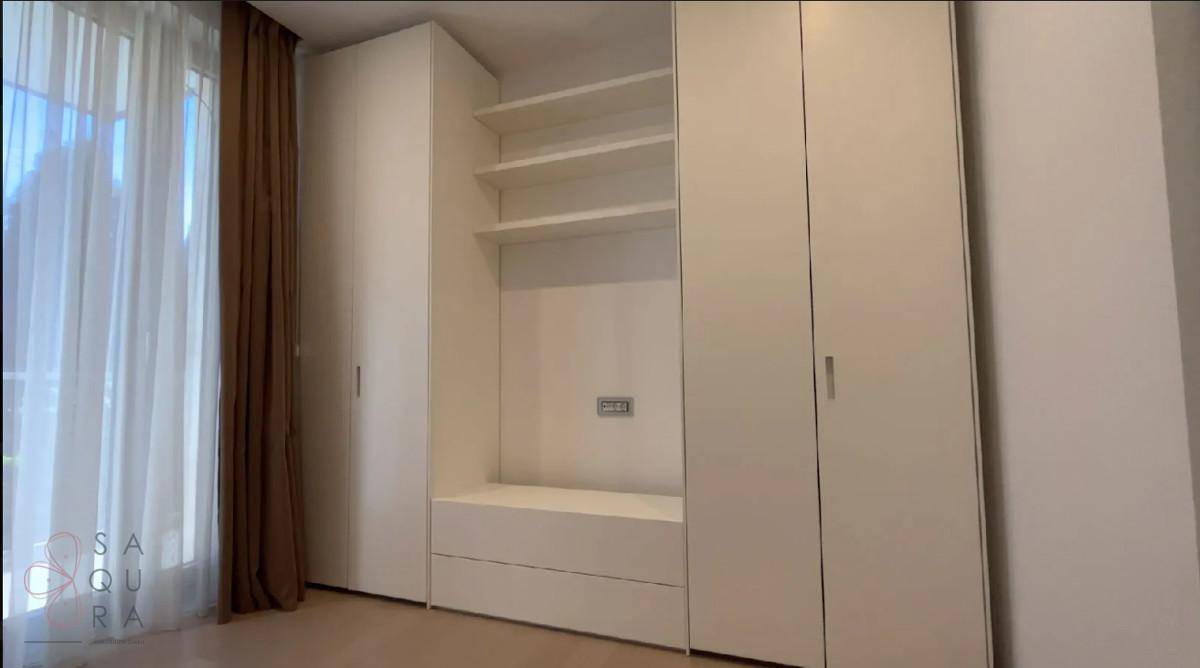 Schlafzimmer mit weißen Einbauschränken, offenen Regalen und großen Fenstern.