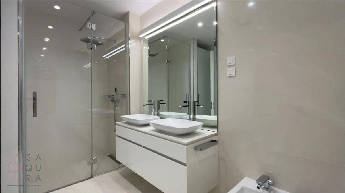 Modernes Badezimmer mit Doppelwaschbecken, großer Spiegelfläche und begehbarer Dusche.