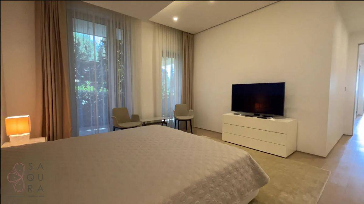 Geräumiges Schlafzimmer mit großen Fenstern, Vorhängen und einem modernen Bett.