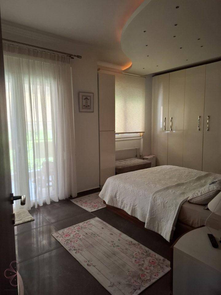 Schlafzimmer mit Doppelbett, Einbauschränken und Zugang zu einem Balkon oder einer Terrasse.