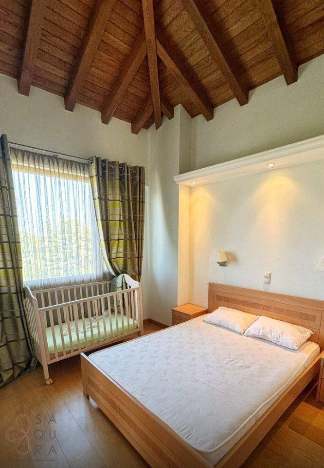 Schlafzimmer mit beeindruckender Holzgewölbedecke, Doppelbett und Babybett.