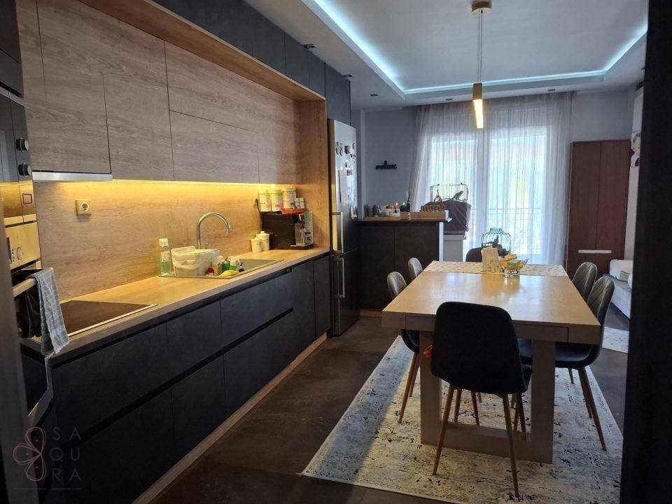 Moderne Küche mit Holz- und Anthrazitfronten, integrierten Geräten und großem Esstisch.