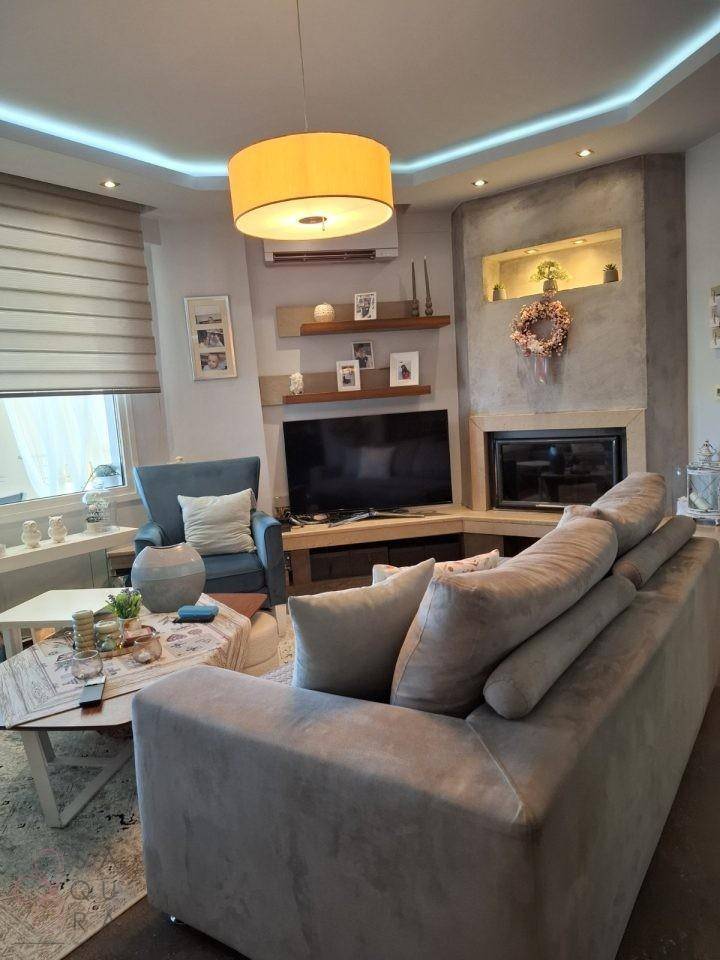Modernes Wohnzimmer mit Kamin, Fernseher und bequemer Sitzecke, hell beleuchtet.