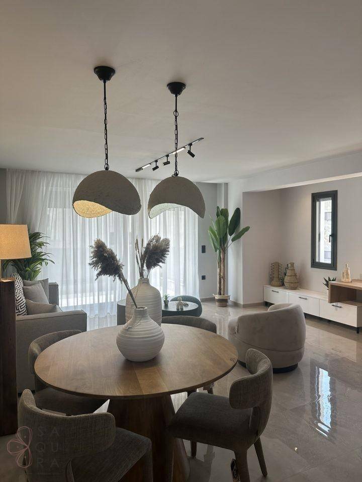 Essbereich mit Holztisch und modernen Pendelleuchten, offen zum Wohnzimmer.