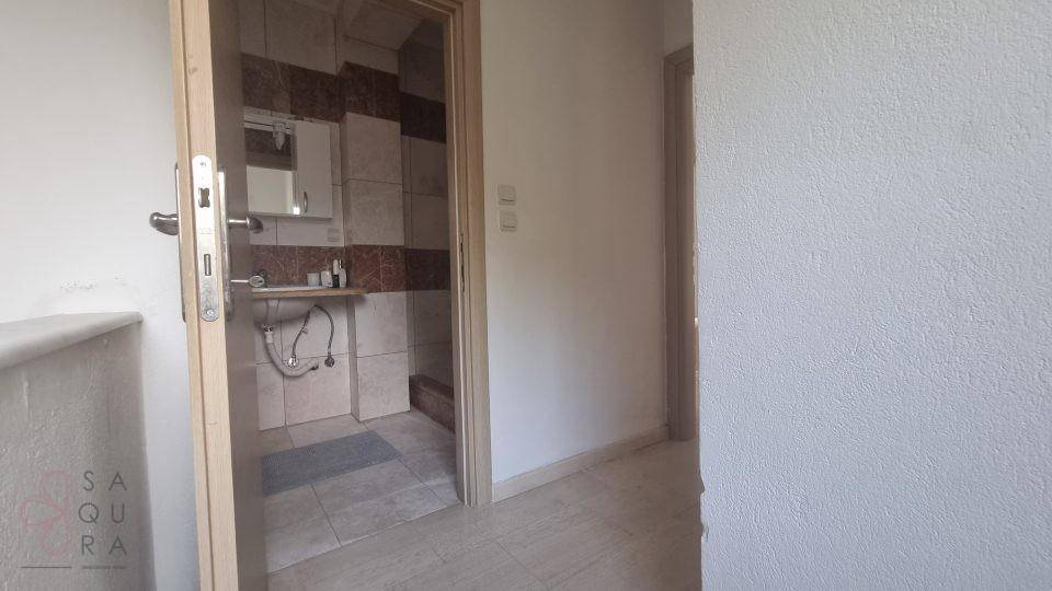Blick in ein Badezimmer mit gefliesten Wänden und einem Waschbecken.
