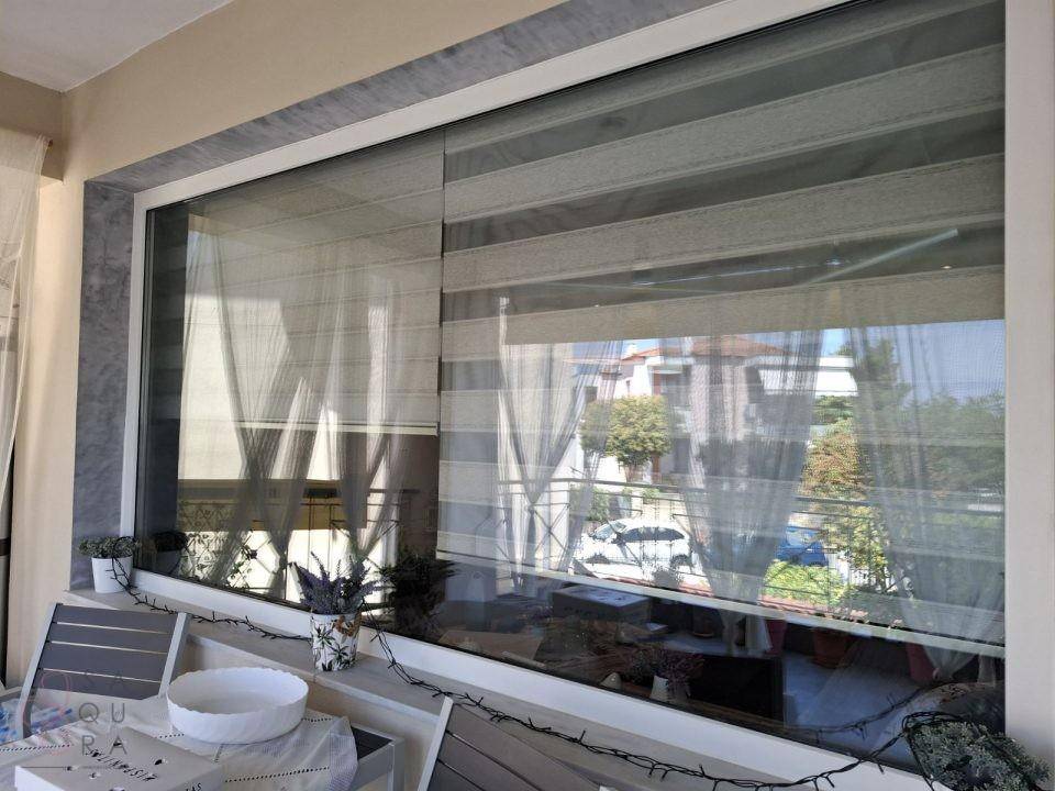Fenster mit modernen Jalousien und Blick nach draußen, das Tageslicht regulierend.