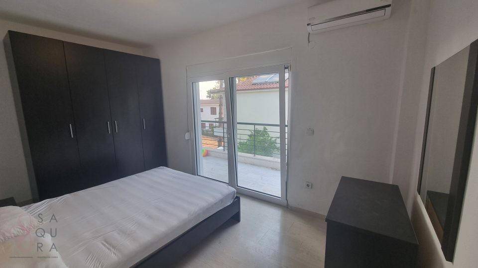 Schlafzimmer mit Doppelbett, Kleiderschrank, Klimaanlage und Balkonzugang.