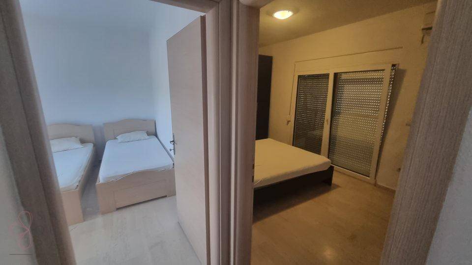 Blick in zwei Schlafzimmer mit Betten und Holzböden.