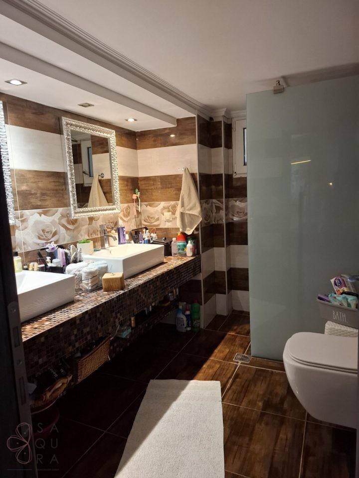Geräumiges Badezimmer mit Doppelwaschbecken, begehbarer Dusche und dekorativen Fliesen.