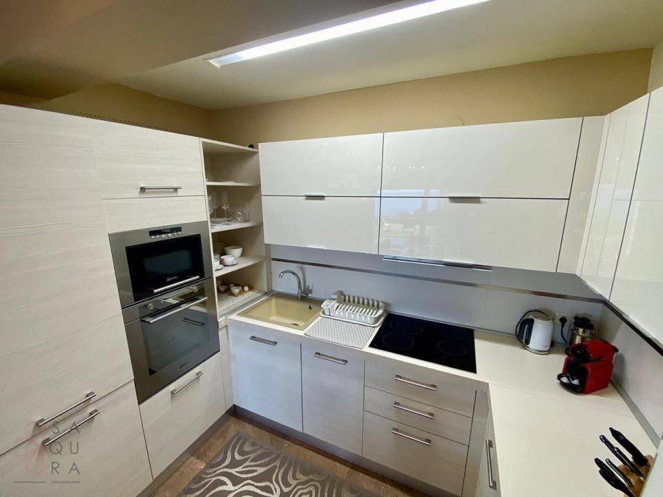 Moderne Küche mit hellen Hochglanzfronten, integrierten Geräten und Induktionskochfeld.