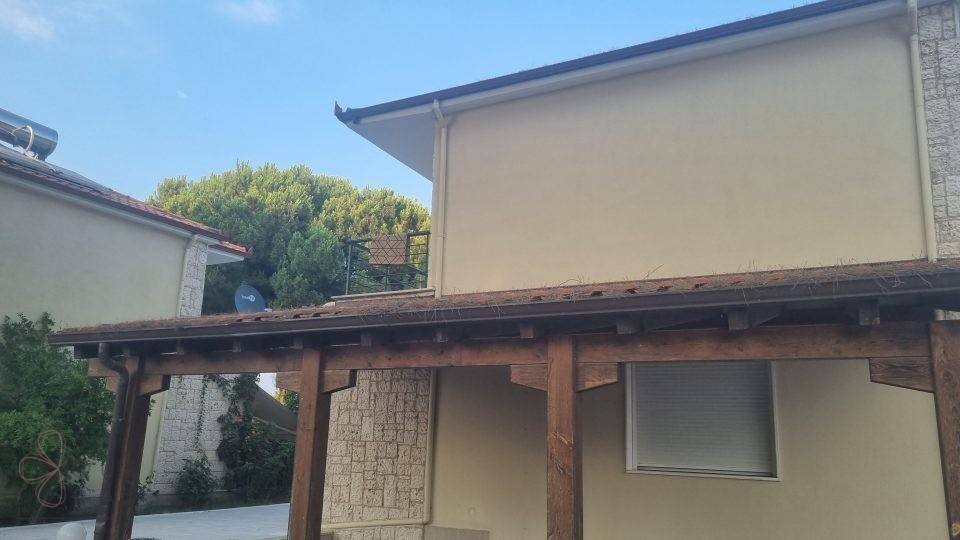 Seitenansicht des Hauses mit überdachtem Bereich und Solaranlage auf dem Dach.