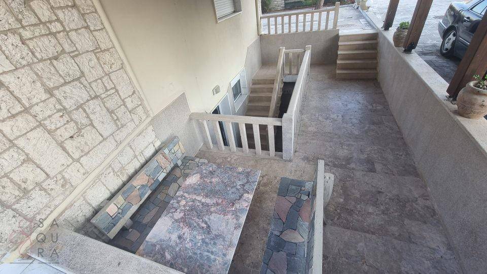 Außenterrasse mit Steinfliesen, Sitzgelegenheiten und Treppen, die zu verschiedenen Ebenen führen.