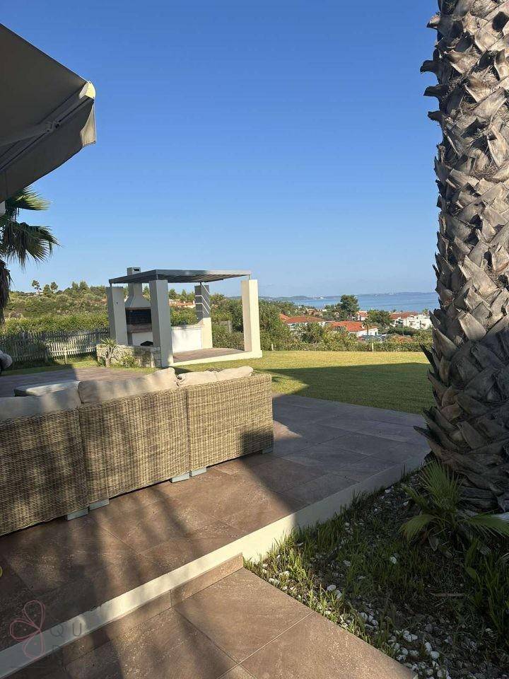 Weitläufiger Meerblick von der Terrasse mit integriertem Grillbereich und grüner Landschaft.