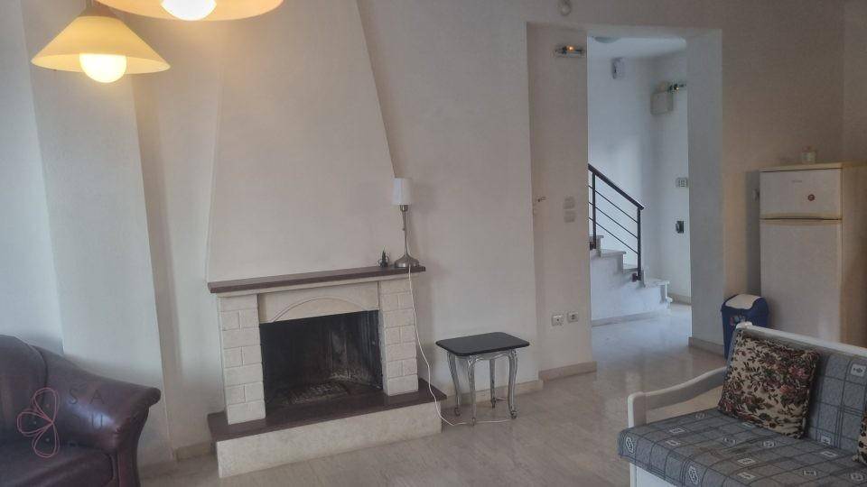 Gemütliches Wohnzimmer mit Kamin, Sofa und Zugang zu einer Treppe.