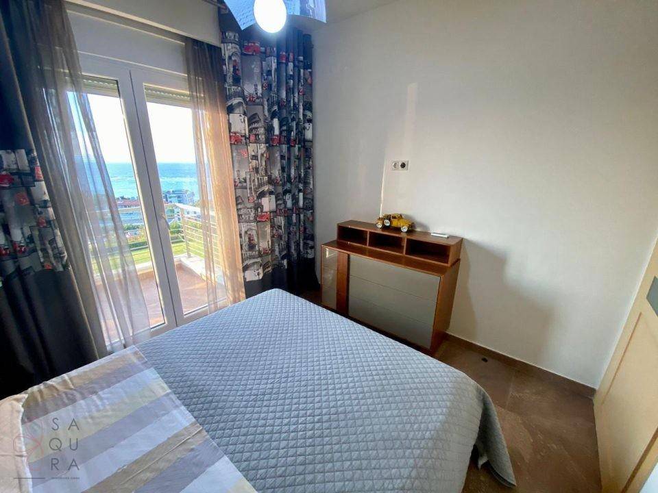 Helles Schlafzimmer mit Balkonzugang, Meerblick und modernen Vorhängen.