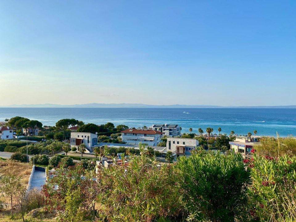Panoramablick auf das Meer und die Küstenlandschaft mit umliegenden Häusern und viel Grün.