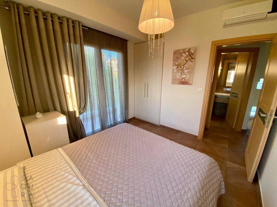 Schlafzimmer mit Doppelbett, Einbauschränken und Zugang zu einem weiteren Badezimmer.