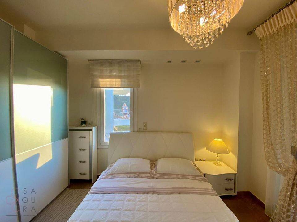 Helles Schlafzimmer mit Doppelbett, Nachttischen und einem Kronleuchter, der eine gemütliche Atmosphäre schafft.