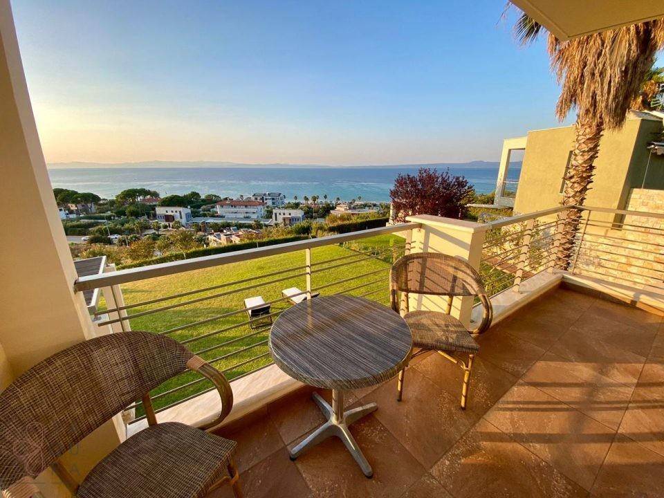 Sonniger Balkon mit Rattanmöbeln und Panoramablick auf das Meer und die Küstenlandschaft.