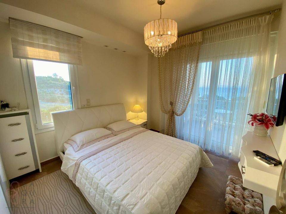 Gemütliches Schlafzimmer mit Meerblick, Balkonzugang und einem eleganten Kronleuchter.