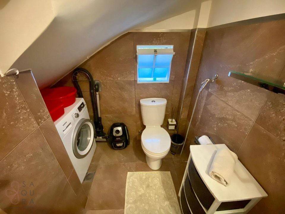 Funktionales Badezimmer mit Waschmaschine, WC und Waschbecken unter einer Dachschräge.
