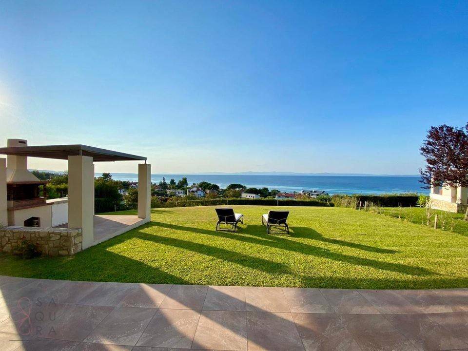 Großer, sonniger Rasenbereich mit Grillplatz und weitem Blick auf das blaue Meer.