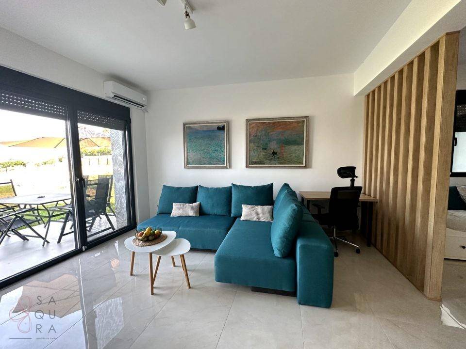 Modernes Wohnzimmer mit tealfarbener Couch, Schreibtisch und Holztrennwand, hell und einladend.