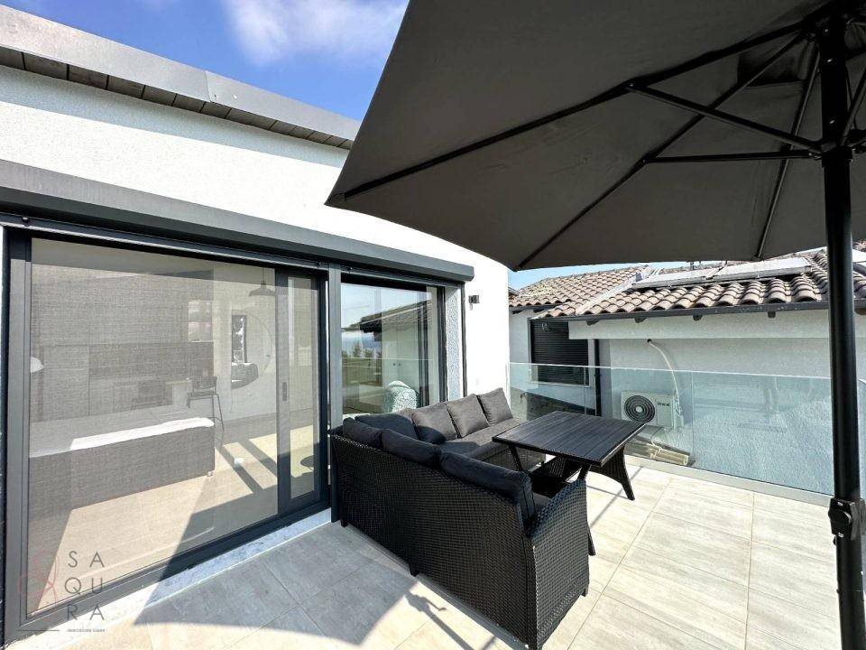 Überdachter Balkon mit Outdoor-Sitzgruppe und Sonnenschirm, ideal für entspannte Momente im Freien.