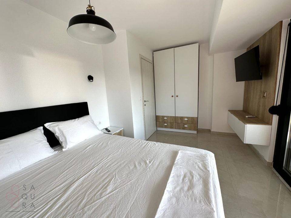 Helles Schlafzimmer mit Doppelbett, Einbauschrank und modernem Wandpaneel mit Fernseher.