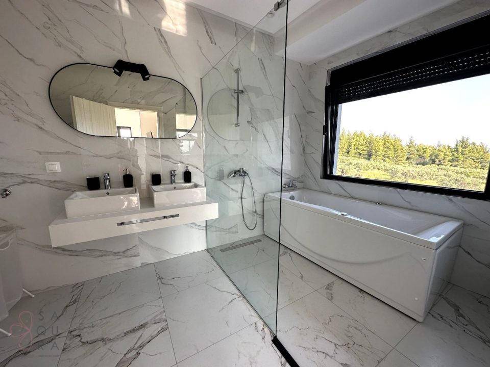 Luxuriöses Badezimmer mit Doppelwaschbecken, Badewanne und großen Marmorfliesen, hell und geräumig.