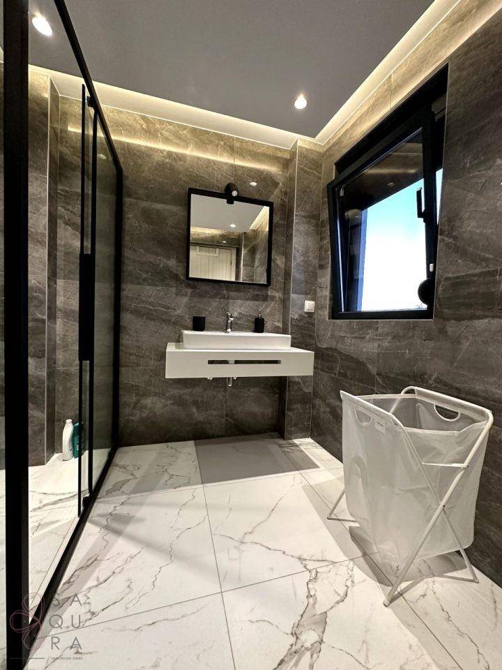 Modernes Badezimmer mit dunklen Wandfliesen, schwebendem Waschtisch und großer Duschkabine.