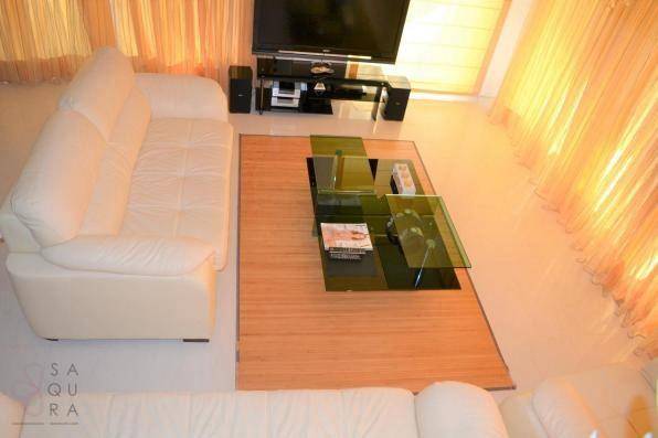 Gemütlicher Wohnbereich mit beigen Sofas, modernem Glastisch und großem Fernseher.
