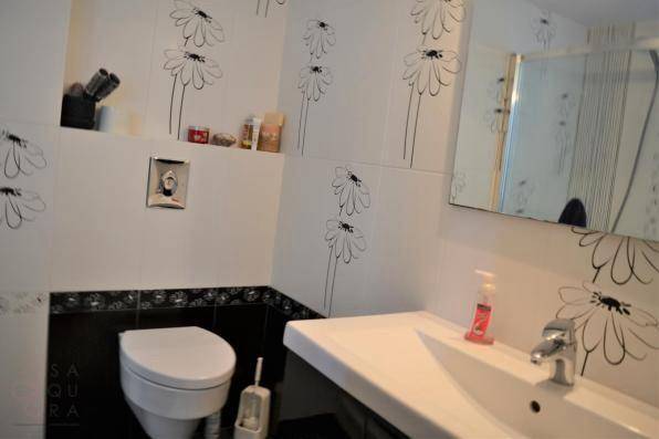 Modernes Gäste-WC mit floralen Wandfliesen, wandhängendem WC und Waschbecken.