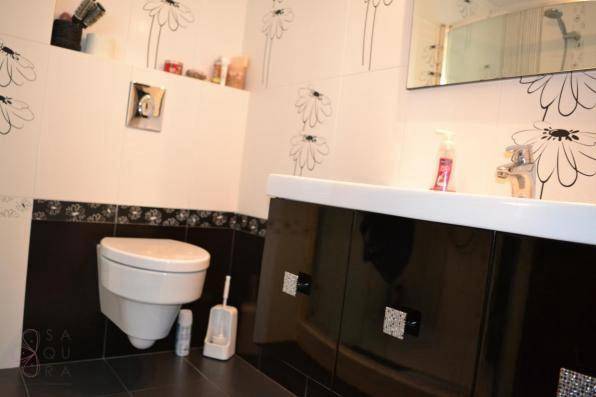 Gäste-WC mit floralen Wandfliesen, schwarzem Unterschrank und modernem Waschbecken.
