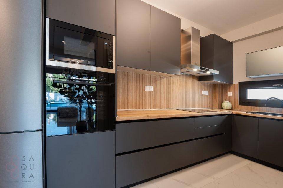 Hochwertige Küche mit integriertem Backofen, Mikrowelle und stilvoller Dunstabzugshaube.