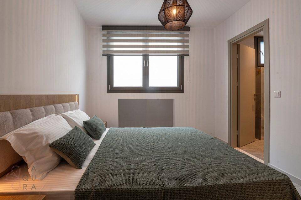 Gemütliches Schlafzimmer mit Doppelbett, Fenster und Zugang zu einem angrenzenden Raum.