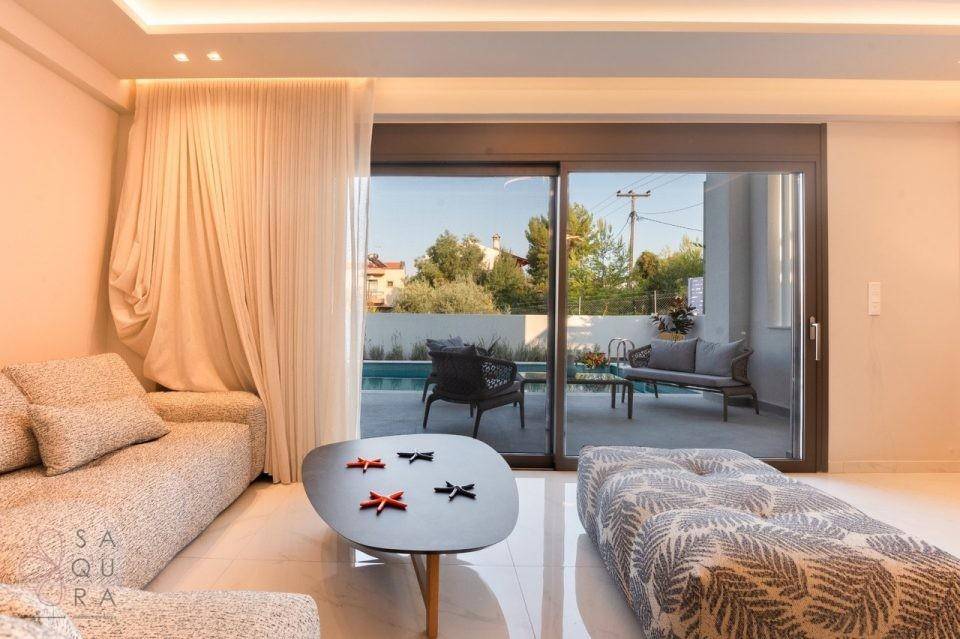 Helles Wohnzimmer mit modernen Möbeln und großem Schiebefenster zur Terrasse und zum Pool.