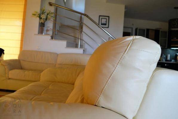 Komfortabler Wohnbereich mit beigen Sofas und Blick auf die Treppe mit Edelstahlgeländer.