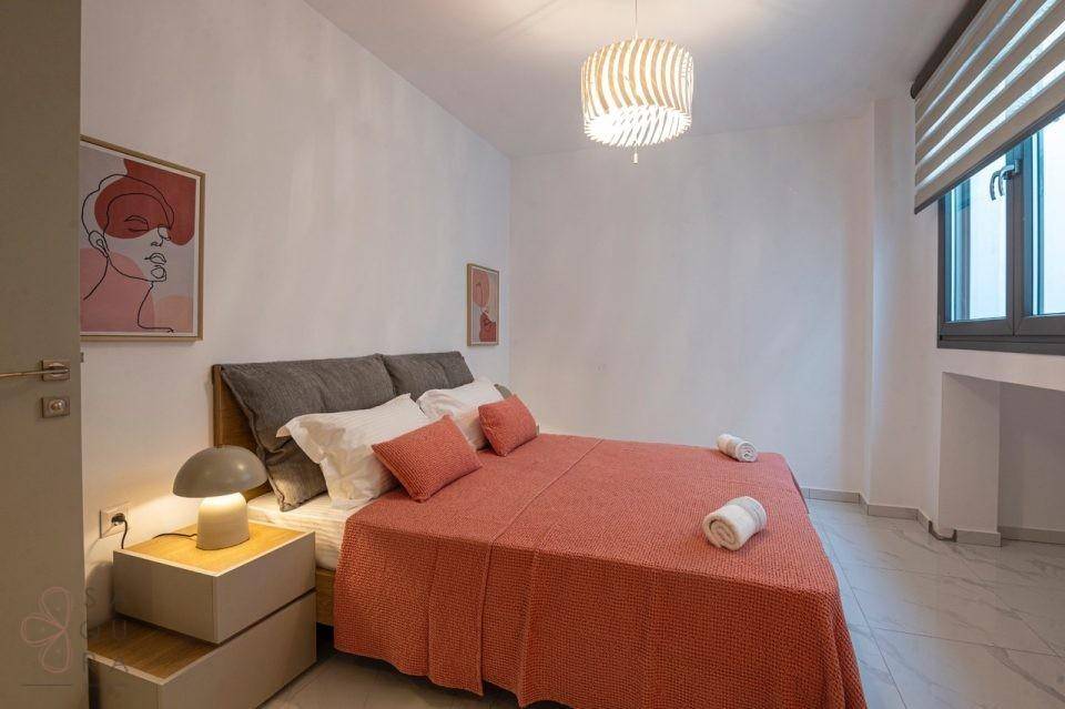 Freundliches Schlafzimmer mit Doppelbett, farbiger Bettwäsche und modernem Fenster.